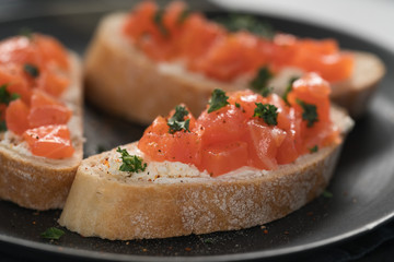 Bruschettas with salmon and cream cheese on black plate closeup