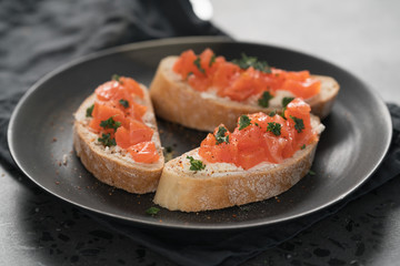 Bruschettas with salmon and cream cheese on black plate closeup