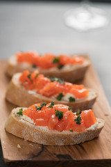Bruschettas with salmon and cream cheese on olive wood board