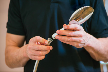 Close-up a man in a dark T-shirt holds in a water mixer for a shower room