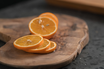 Sliced orange lemon on olive wood board closeup