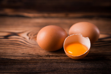 Detail close-up of chicken eggs on the old brown wooden background.