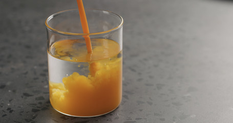 sea buckthorn juice pour into beaker glass with water on concrete surface