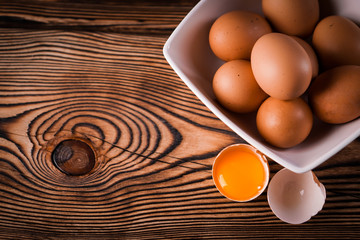 Detail close-up of chicken eggs on the old brown wooden background.