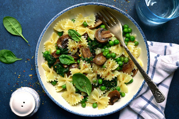 Pasta farfalle with mushrooms, spinach and green pea. Top view with copy space.