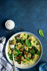 Pasta farfalle with mushrooms, spinach and green pea. Top view with copy space.