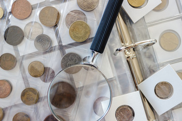 Ukraine, Sumy, October 11, 2019. Different old collector's coins with a magnifying glass