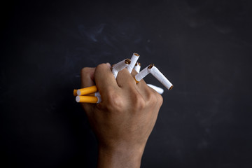 Man hand holding and destroy cigarettes on black background. Quitting smoking concept. world no...