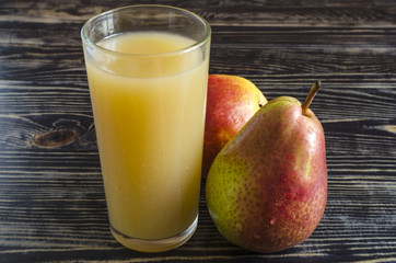 a glass of pear juice and juicy pears on a dark wooden background close up