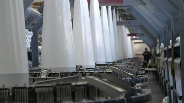 Line of conical columns rotating and making plastic canvas for agro sacks at plant