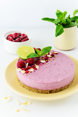 Raw cashew cake with raspberries and lime on a light plate. Vegan dessert, sugar free, gluten free, lactose free.