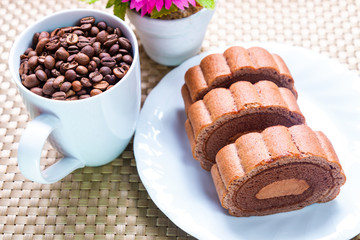 Delicious roll cake with coffee beans in cup