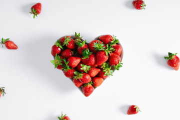 Strawberry. Juicy strawberries in white plate in shape of heart on white background. Flat lay, top view, copy space