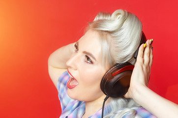 beautiful blonde with headphones posing on a red background