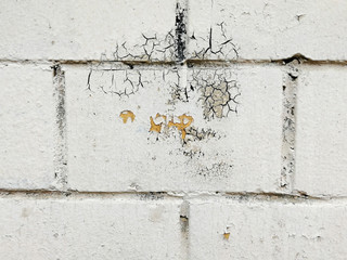 Close up of a white brick wall with weathered and damaged paint