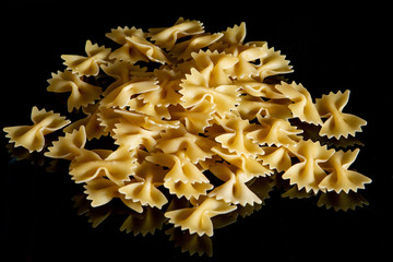 Farfalle raw pasta on black background. Cooking concept. Top view with copy space.