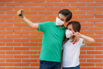 Happy Little boy and girl wearing mask and taking a selfie with the smartphone