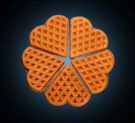 Five fresh heart-shaped waffles isolated on a black background. Homemade baking.