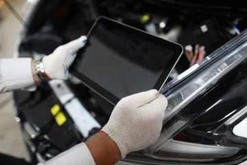 Mechanic holding tablet to diagnose auto condition