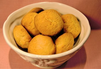 Homemade macaroons in a beige ceramic bowl on a background of pink linen cloth