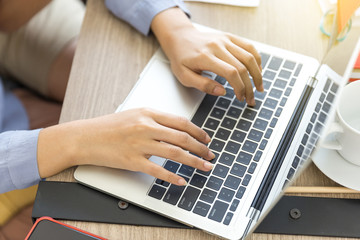 The hands of a woman are using a laptop computer to working at home. Working from home or working at home concepts.