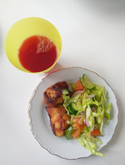 plate with a delicious salad of vegetables and meat steak and a glass of juice, top view