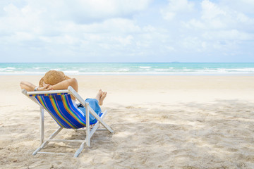 Fototapeta na wymiar Young Beautiful Asian woman relax in the sun on chairs on the beach near the sea. enjoying looking view of sea with blue sky on summer vacation and travel holiday concept.