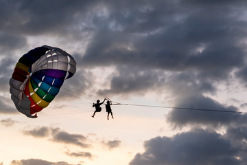 people ride, fly on a parachute along the coast over the sea against the background of a wonderful sunset. Attraction entertainment for tourists in the sea resorts of Thailand, Asia and around the