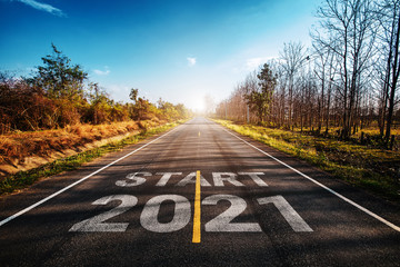 The word start 2021 written on highway road in the middle of empty asphalt road at golden sunset and beautiful blue sky. Concept for new year 2021.