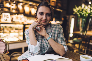 Thoughtful woman with clasped hands sitting in cafe