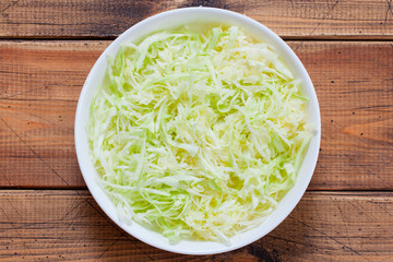 Step-by-step preparation of salad with fresh cabbage, sausages and canned green peas, step 2- chopped fresh cabbage, top view, selective focus