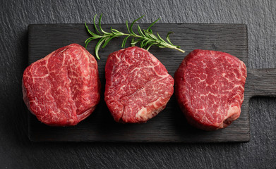 Raw beef fillet steaks on black background top view