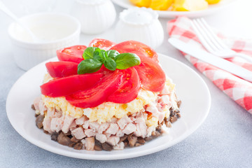 Festive layered salad with fried champignons, smoked chicken, eggs and cheese, garnished with fresh tomatoes, selective focus