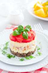 Festive layered salad with fried champignons, smoked chicken, eggs and cheese, garnished with fresh tomatoes, selective focus