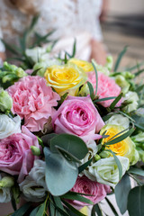 close up bride's bouquet of roses (pink, yellow, white); the bride holds a bouquet of flowers in her hands (vertically)