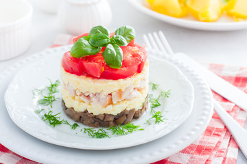 Festive layered salad with fried champignons, smoked chicken, eggs and cheese, garnished with fresh tomatoes, selective focus