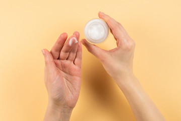 Hand cream and woman hands on a beige background.