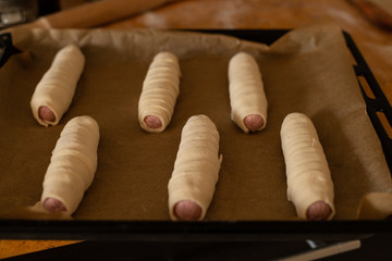 the process of cooking homemade sausages in the dough, sausages in the dough on a baking sheet ready for baking