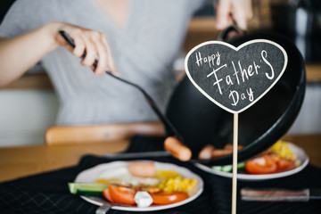 Happy father's day. Chalk plate with the inscription on the background of the wife who is preparing homemade breakfast.