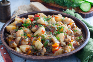 Vegetable stew with potatoes and eggplant in a clay bowl, vegetarian recipe, selective focus