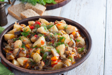 Vegetable stew with potatoes and eggplant in a clay bowl, vegetarian recipe, selective focus