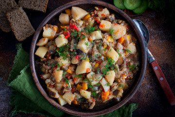 Vegetable stew with potatoes and eggplant in a clay bowl, vegetarian recipe, selective focus