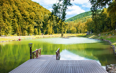 Wooden pier on the lake against the background of the forest and mountains.