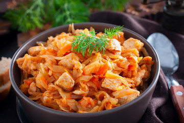 Braised cabbage with chicken breast in a clay bowl, selective focus