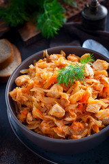 Braised cabbage with chicken breast in a clay bowl, selective focus
