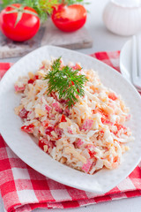 salad with crab sticks, tomatoes, cheese on a white dish, selective focus