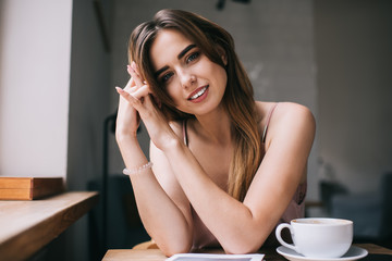 Naklejka premium Cheerful young woman at table with coffee and magazine