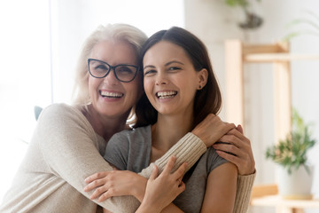 Portrait of happy senior 60s mom and grown-up daughter hug cuddle enjoy weekend time together,...