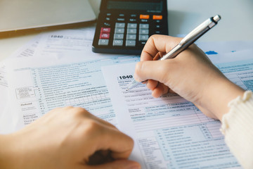 Close up woman hand filing US tax form. tax form us business income office hand fill...