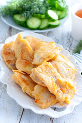 Pollock fillet in batter on a white plate, selective focus